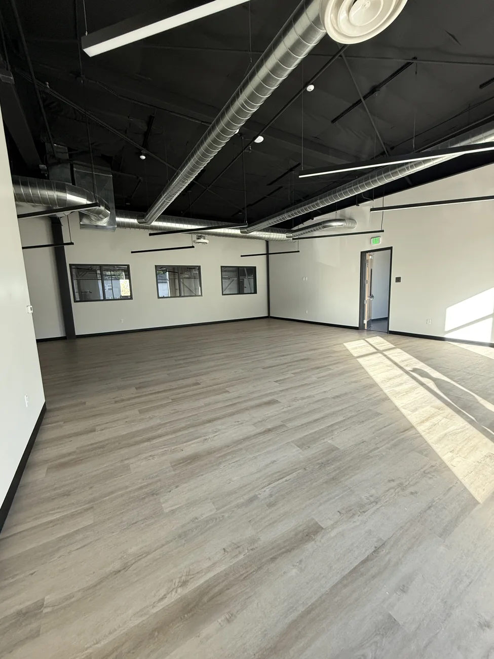 Finished office space with windows, wood-look flooring, and exposed ceiling in the Farmington commercial building