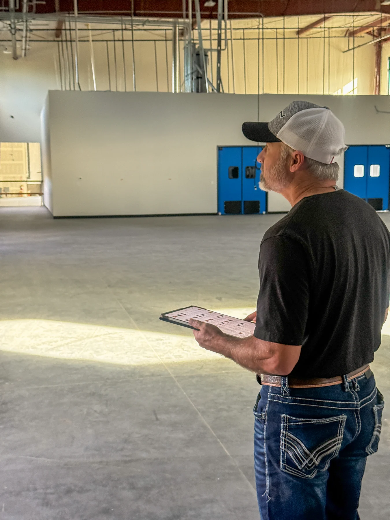 Building professional reviewing project details on a tablet inside a steel building